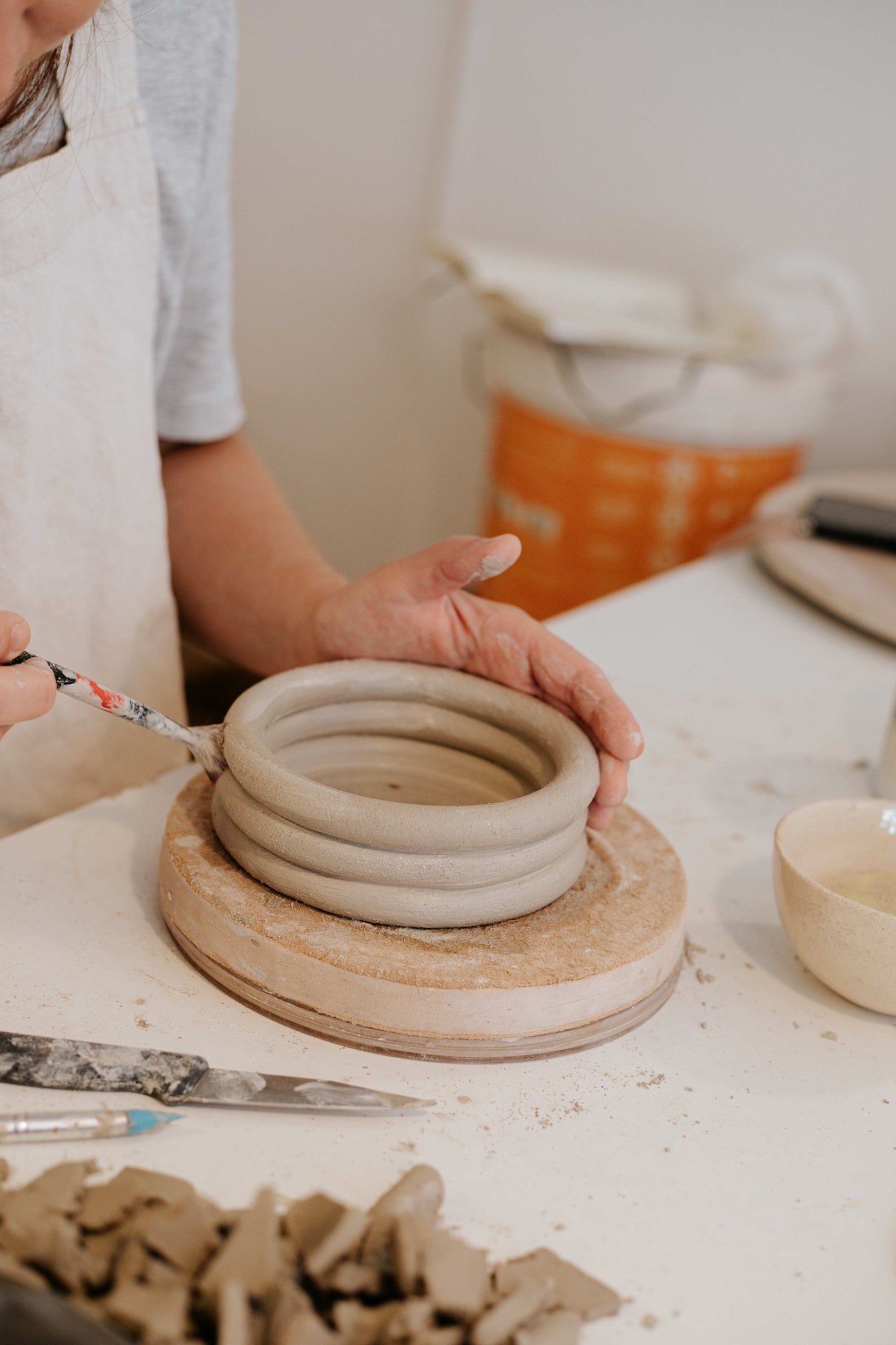 Person working with clay on a pottery wheel in a studio setting