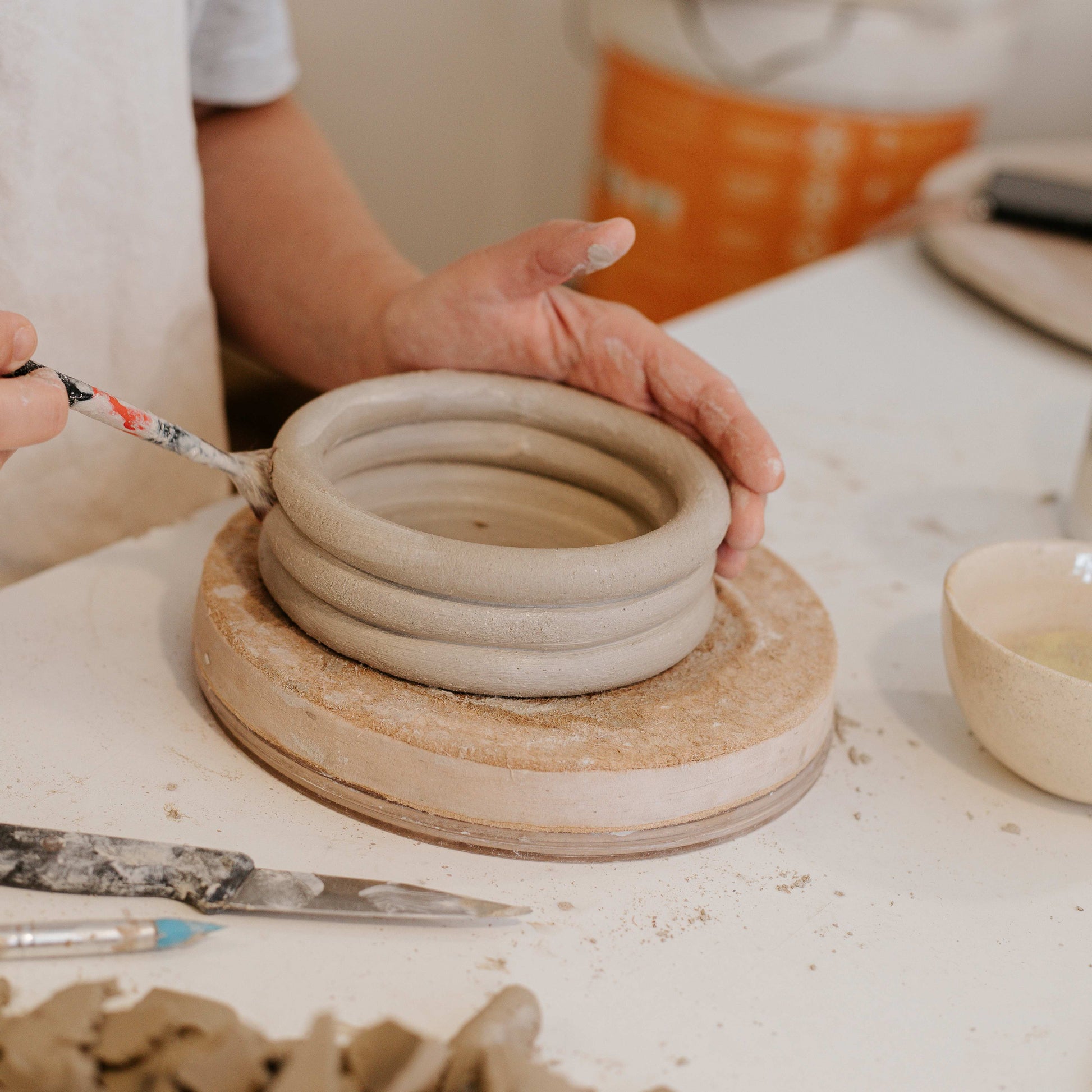 Person working with clay on a pottery wheel in a studio setting