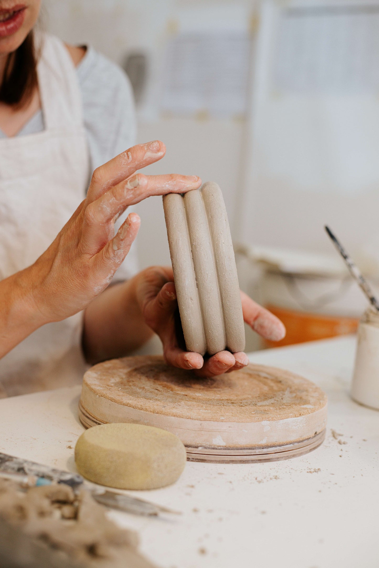 Person holding a stack of ceramic cylinders on a pottery workshop