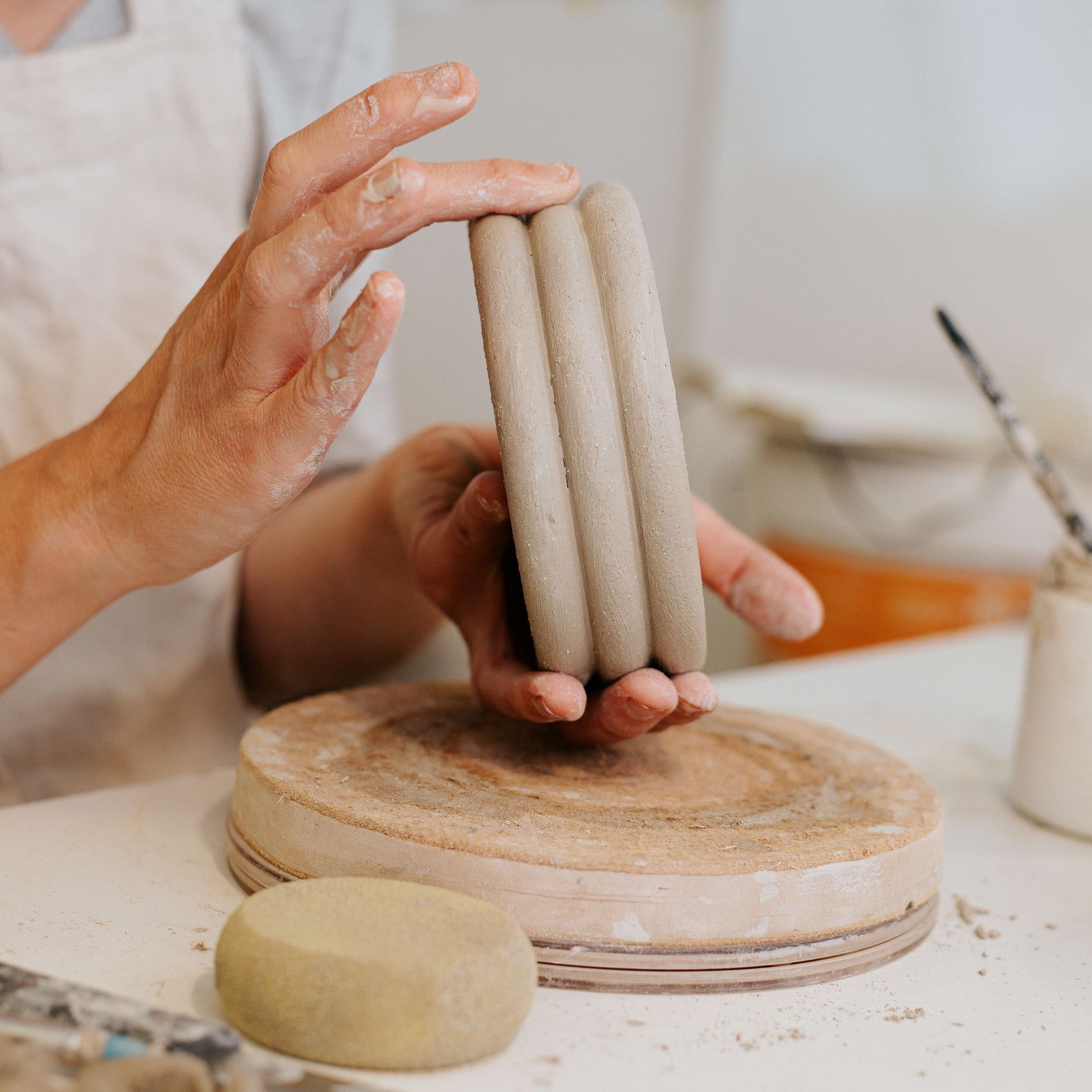 Person holding a stack of ceramic cylinders on a pottery workshop